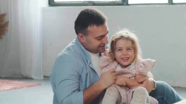 Padre haciendo cosquillas a su hija mientras juegan juntos en la alfombra en el suelo. — Vídeo de stock