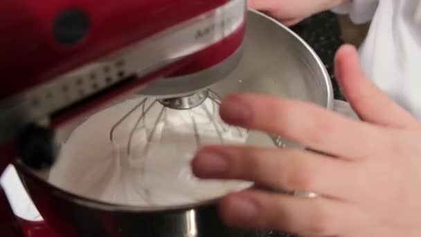 Gros plan d'un mélangeur de stand rouge qui fouette la crème dans un bol en acier inoxydable. — Video