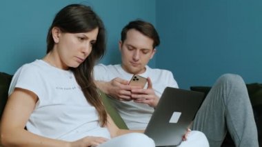 Evde aile işi, dizüstü bilgisayar kullanan bir kadın ve smatfon kullanan bir adam..