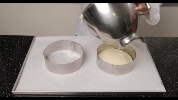 Žena ruce nalévání těsto na dort do formy pomocí špachtle a nerezové misky. — Stock video