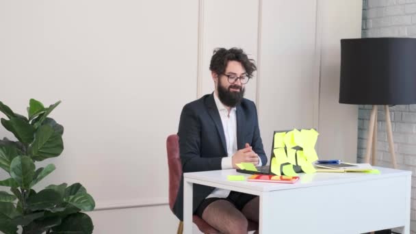 Baard man comfortabel aan zijn bureau, in ondergoed en jas werken op afstand. — Stockvideo