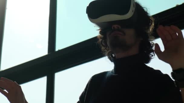 VRメガネの男は周りを見回し、手で何かに触れようとします. — ストック動画