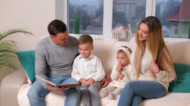 親愛なる家族、父は居間に座っている家族に本を読む. — ストック動画