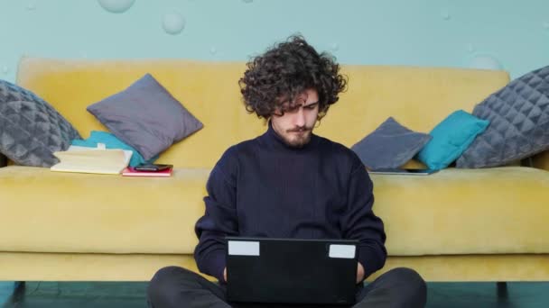 Unge man bläddrar på sin bärbara dator och sträcker upp händerna, arbetar på den bärbara datorn. — Stockvideo