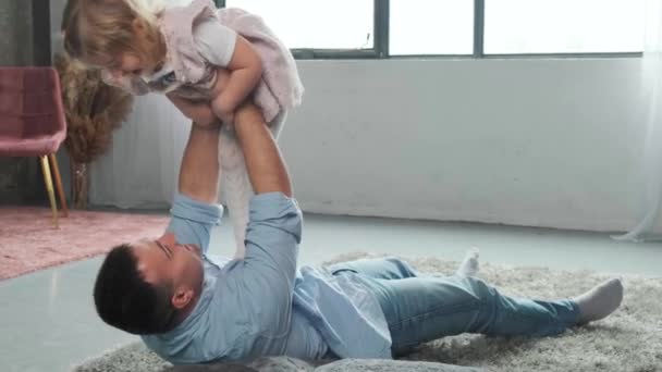 Kleines Mädchen spielt mit ihrem Vater, während ihre Mutter mit einem Tablet arbeitet. — Stockvideo