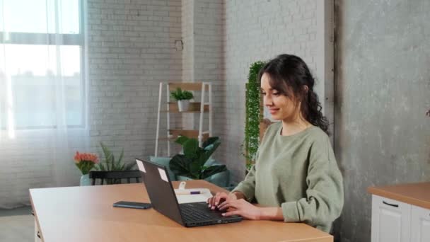 Schöne junge Frau, die mit Laptop arbeitet und vor Freude die Hände hebt. — Stockvideo