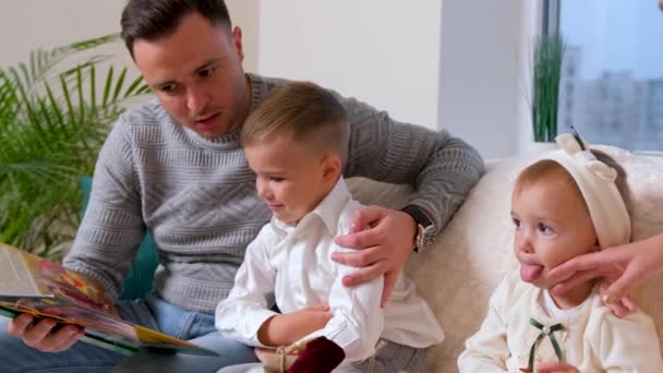 可爱的家人，父亲坐在客厅里给家人读书. — 图库视频影像