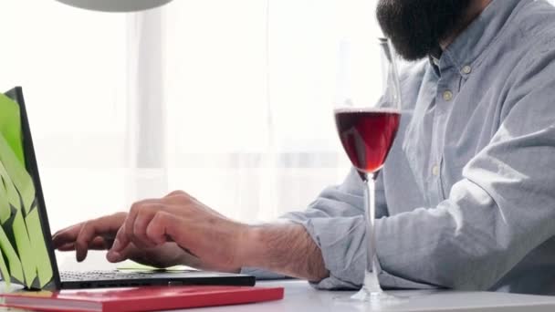 Homem barbudo que trabalha no computador cheio de notas de lembrete, bebe vinho. — Vídeo de Stock