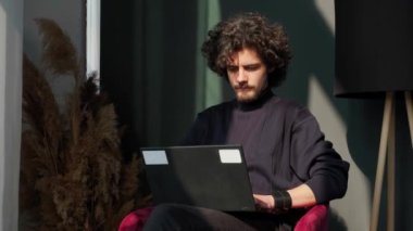 Pencerenin yanında oturan ve gün batımında dizüstü bilgisayarın başında çalışan bir adam manzaraya hayran..