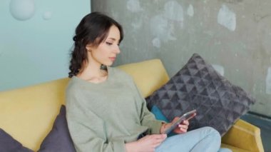 Elinde tablet olan ve komik bir video izleyen bir kadın sosyal medyada sohbet ediyor..