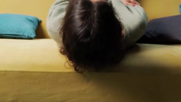 Спокойная девушка лежит на диване и закрывает глаза, отдыхает дома. — стоковое видео