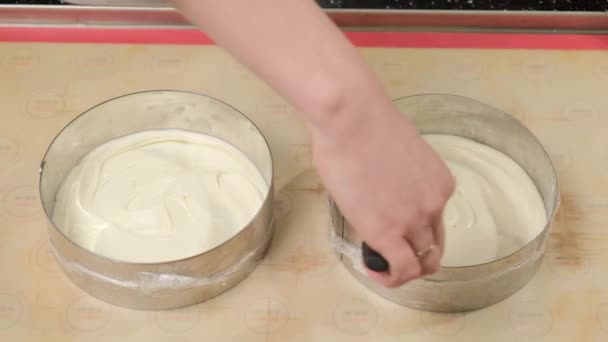 Vrouw handen regelt taart beslag in taart schimmel met behulp van een metalen spatel. — Stockvideo