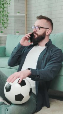 Elinde futbol topu olan ve telefonda konuşan bir adam..