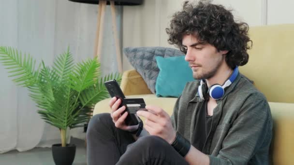 Knap jong krullend harig guy kijken naar de camera met een gelukkig gezicht uitdrukking. — Stockvideo