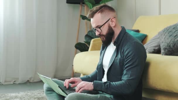 Man arbetar vid datorn med en massa påminnelser anteckningar, sitter nära soffan. — Stockvideo