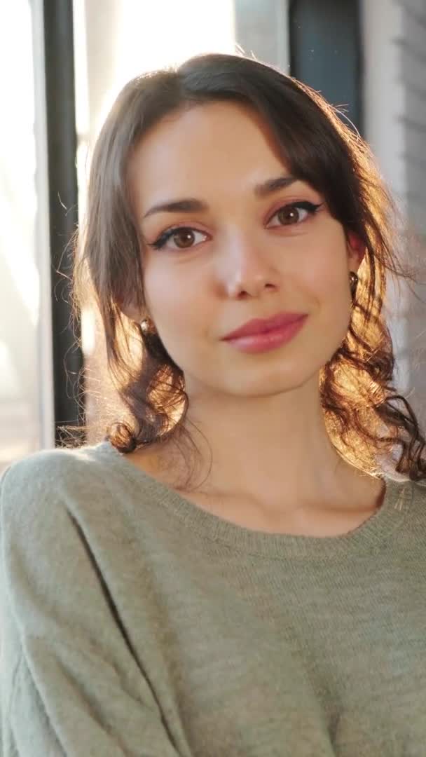 Woman staying near window and flirting at the camera, the sun illuminate her face. — Stock Video