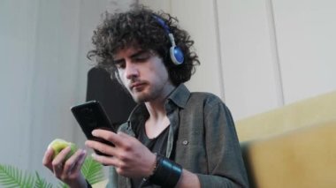 Genç adam elma yerken müzik dinliyor ve dans ediyor..