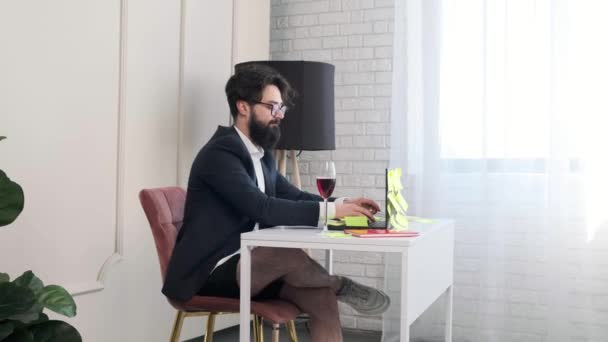 Szakállas férfi nadrág nélkül zárja be a számítógépet és igyon egy pohár bort.. — Stock videók