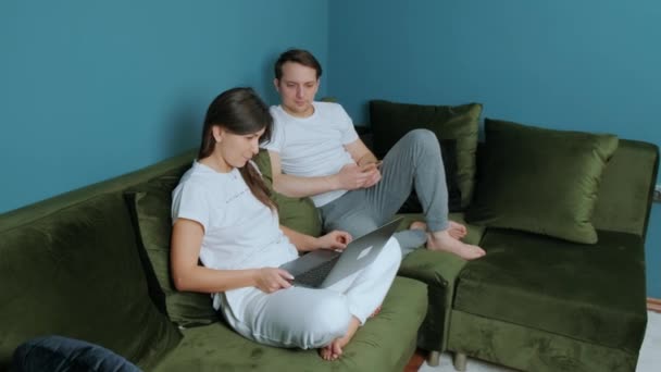Familjearbete hemifrån, kvinna som använder laptop och man som använder smatphone. — Stockvideo