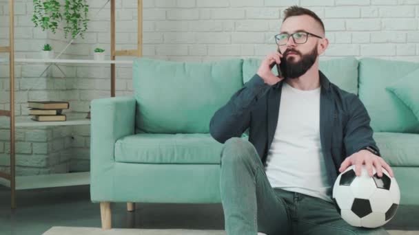 Hombre de pie con pelota de fútbol en las manos y hablando por teléfono. — Vídeos de Stock