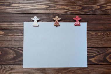 Yılbaşı kartı. Tahta bir masada beyaz boş bir çarşaf. Üç tahta melek figürü. Noel Baba 'ya mektup var. Reklam afişi. Yerleşim planı. maketleme.