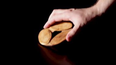 Bir adamın eli masanın üzerine sıcak suyun altında ahşap bir standı ve üstüne de bir fincan koyar. Masada şeffaf bardak var. koyu arkaplan.