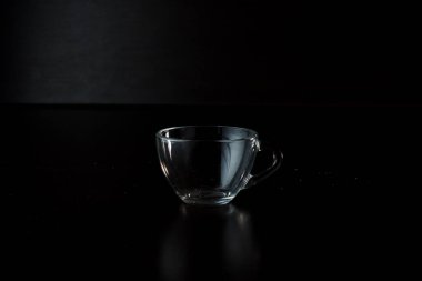 Siyah arka planda şeffaf cam bardak. Masanın üzerinde boş bardak var..