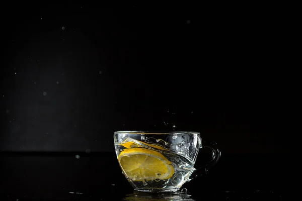 Su sıçrıyor. Dondurma hareketi. Donmuş alkol spreyi. Bir bardak suya bir dilim limon düştü. aksiyonu durdurun. Menü tasarımı Yan görünüş. reklam afişi
