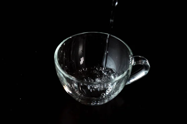 Versando Acqua Bicchiere Tazza Trasparente Con Acqua Sfondo Scuro Getto — Foto Stock