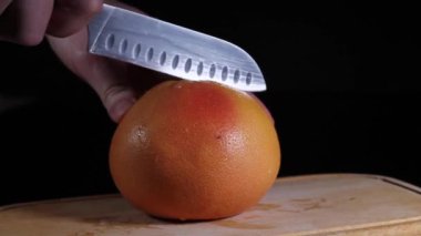 Bir adam greyfurtu ikiye böler. Şef tropikal bir meyve kesiyor..