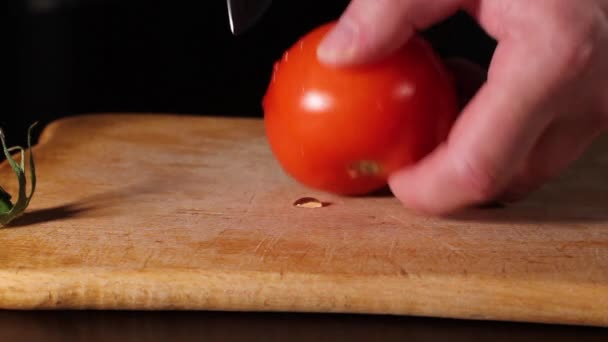 Man snijdt een rijpe rode tomaat met een mes. — Stockvideo