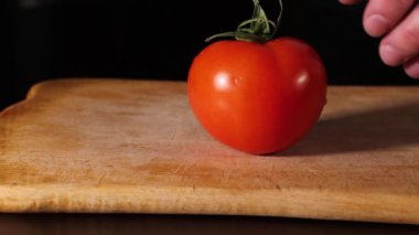 Bir adam domatesin yeşil kuyruğunu koparır. Şef domatesi soyar. yemek salatası.