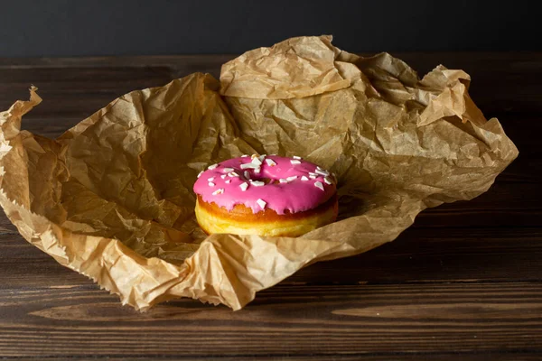 おはようございます 焼きたてのドーナツとクリームとピンクの充填包装紙に包まれて朝食のための木製のテーブルの上に 暗い背景だ テキストの場所 — ストック写真