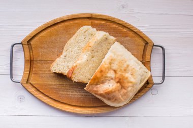 Eski ahşap tahta üzerinde ekmek dilimlenmiş.