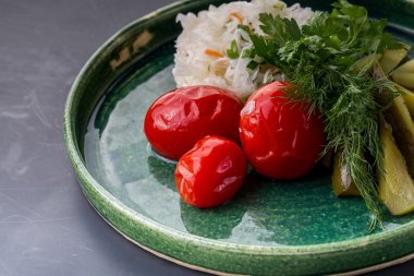 Lahana, turşu ve rustik tabakta domates salatası.