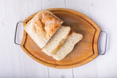 Eski ahşap tahta üzerinde ekmek dilimlenmiş.