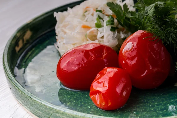 Salade de choucroute, cornichons et tomates dans une assiette rustique . — Photo