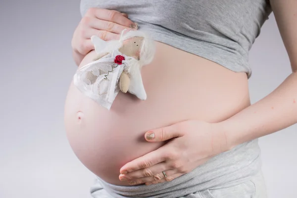 Pregnancy . Pregnant woman holding belly on the little toy fairy — Stock Photo, Image