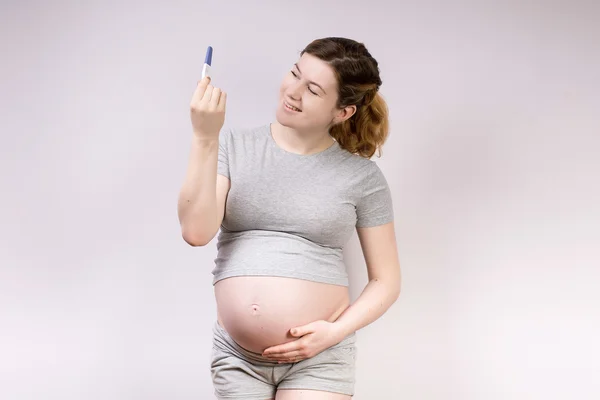 Uma imagem de uma mulher grávida segurando o teste positivo — Fotografia de Stock