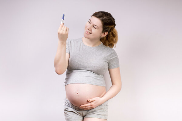 an image of a pregnant woman holding the positive test