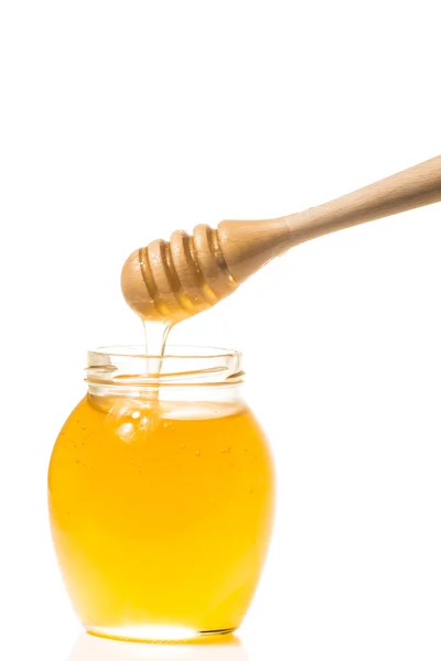 罐蜂蜜与孤立在白色背景上的木制 drizzler — 图库照片