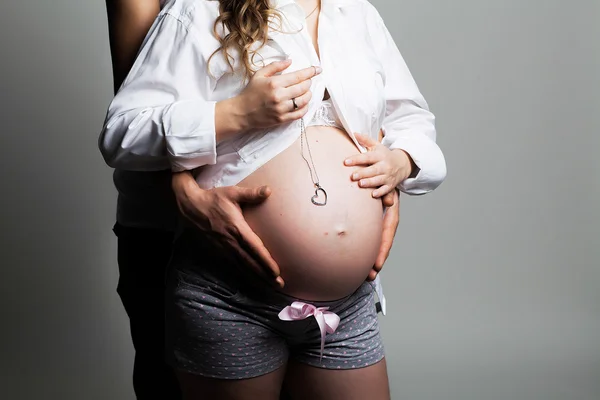 Pregnant young woman with man in studio — Stock Photo, Image