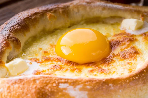 Acaralı khachapuri çiğ yumurta ile ahşap masa üzerinde kapat