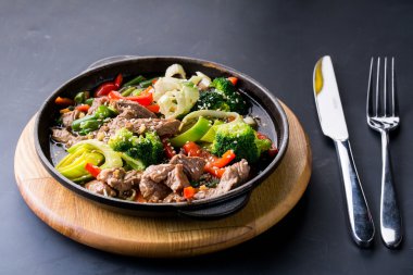 koyu arka plan üzerinde bir tavada sebze ile sığır eti güveç