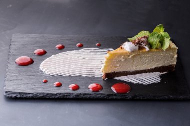 Beyaz ahşap masa üzerinde çilek şurubu ile lezzetli peynirli kek