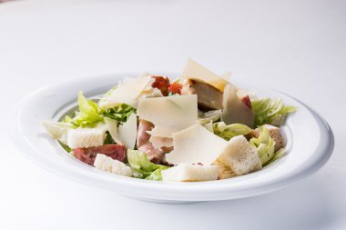 Tavuklu Sezar salatası ve ahşap masada yeşiller.