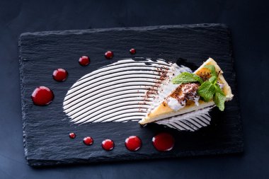 Beyaz ahşap masa üzerinde çilek şurubu ile lezzetli peynirli kek