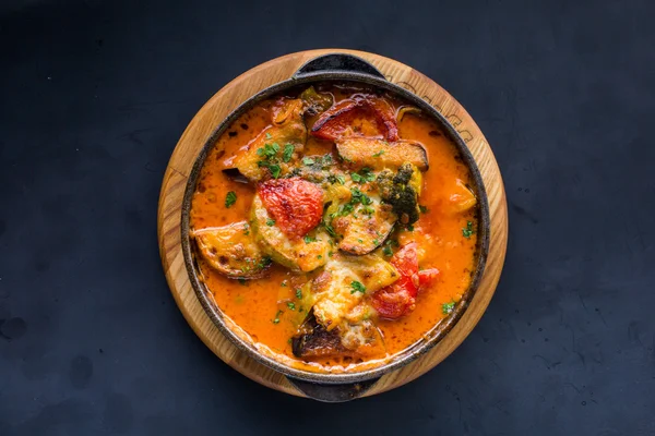 Buğulanmış sebze karanlık masada bir tavada karıştırın