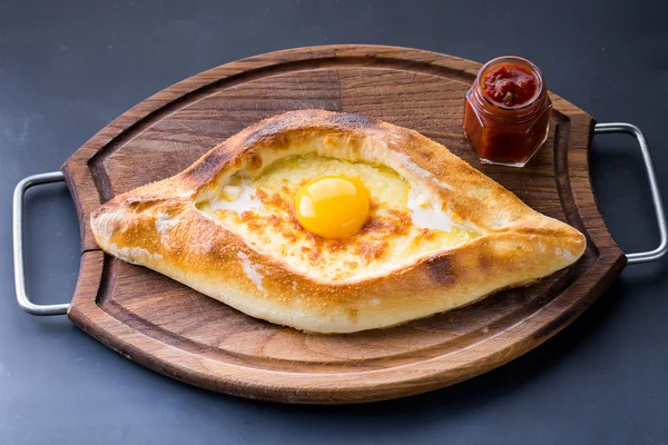 Çiğ yumurta ile karanlık tabloda Acaralı khachapuri yakın çekim