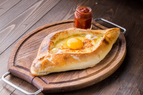 Acaralı khachapuri çiğ yumurta ile ahşap masa üzerinde kapat